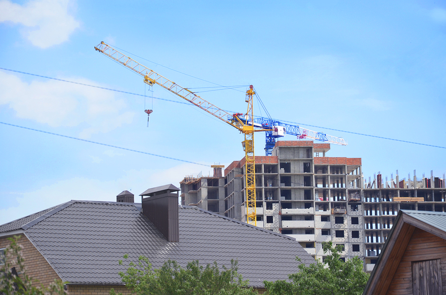 Apartment building under construction with house roof in foreground