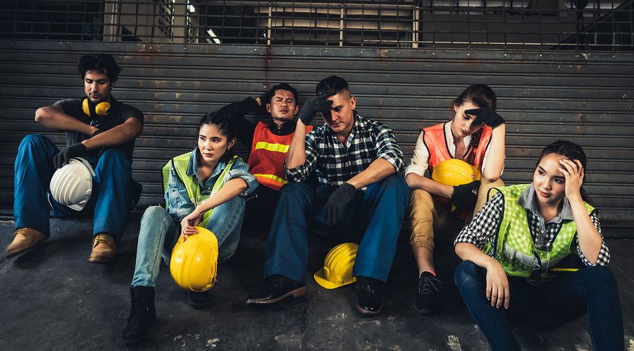 Factory workers in front of closed gate after layoffs