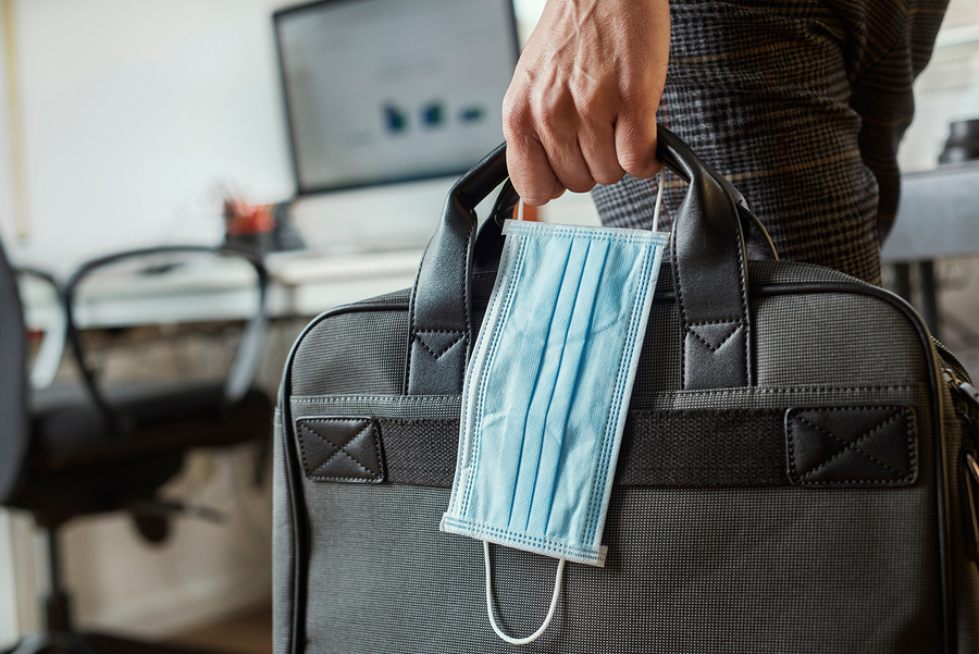 Man carrying face mask and computer bag back to work