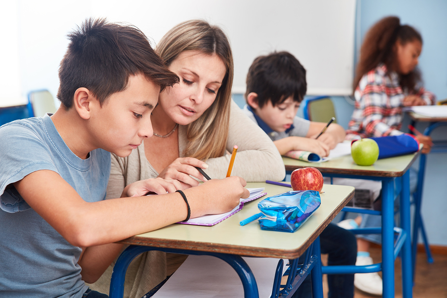 Teacher crouching to help pupil