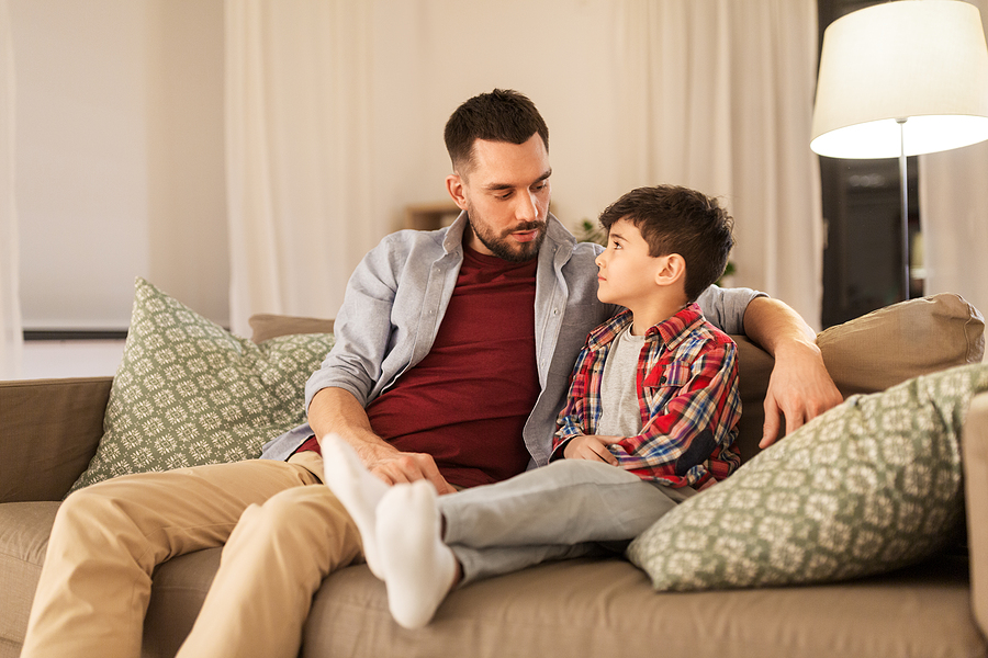 Father and son sit on couch discussing career prospects with an air of gloom hanging over them.