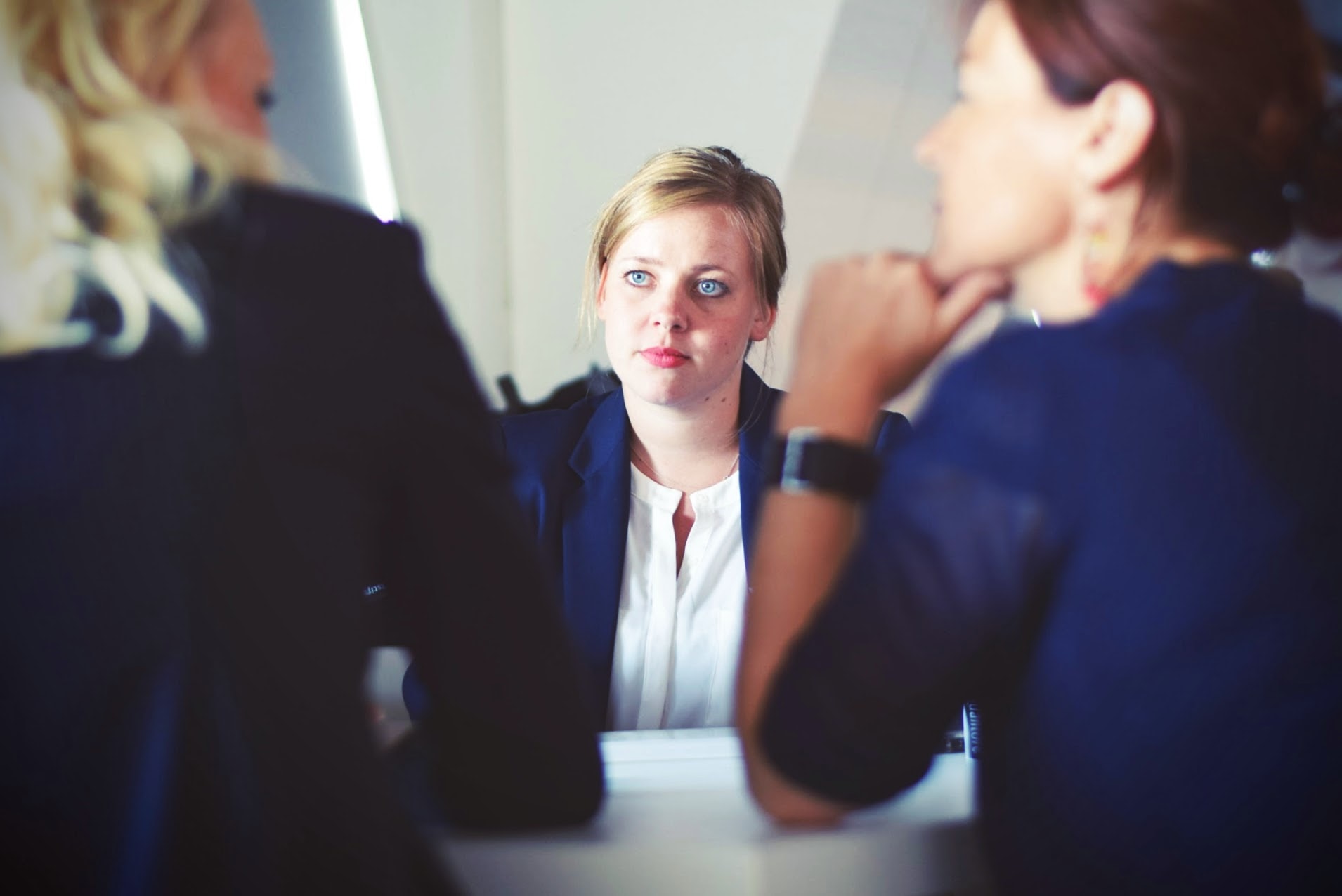 woman in professional attire listens to other businesswomen