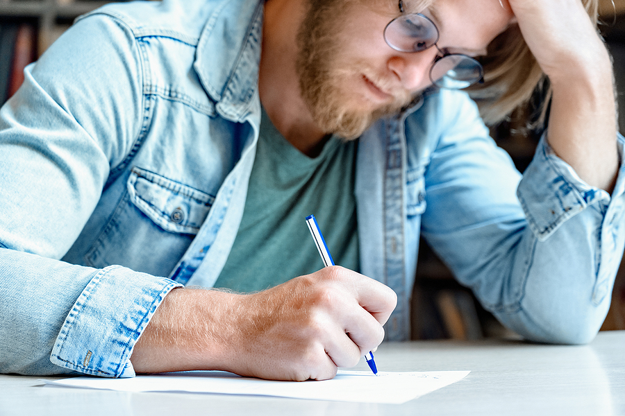 Adult white man in denim shirt fills out written evaluation