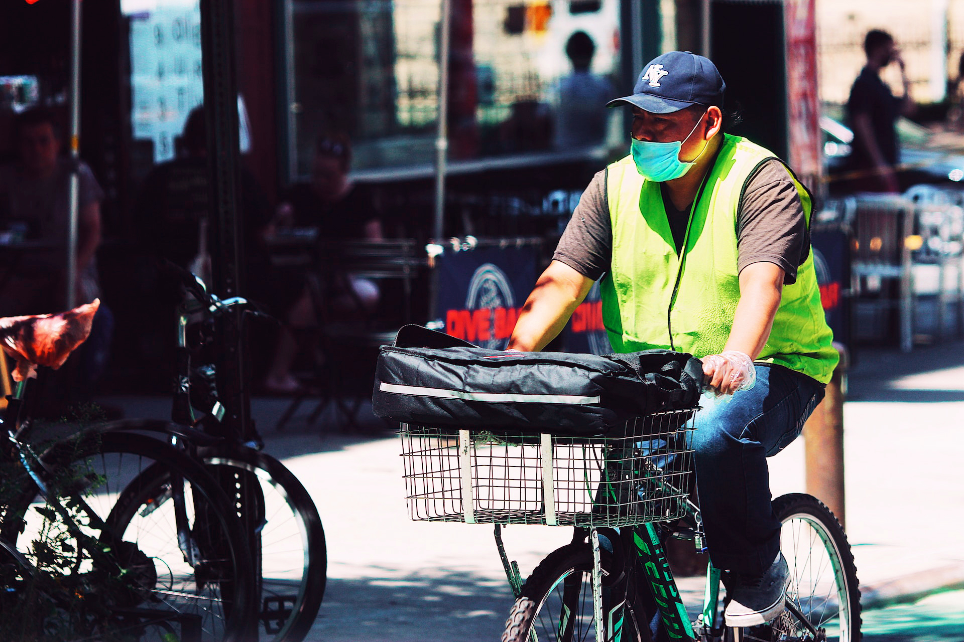 Delivery bicylist wearing high-viz vest, ball cap and covid mask