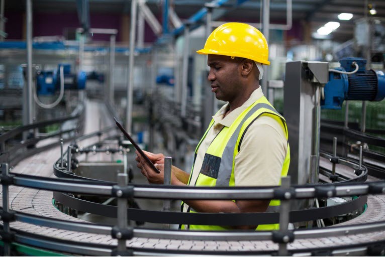 Manufacturing worker in hi-viz clothing and hardhat studies instructions