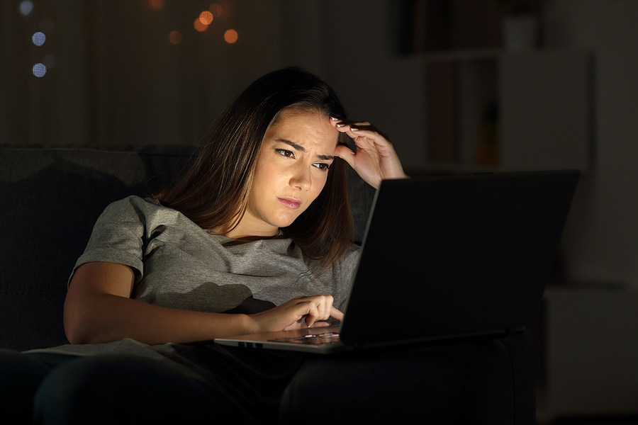 Worried young woman considers her job options on laptop
