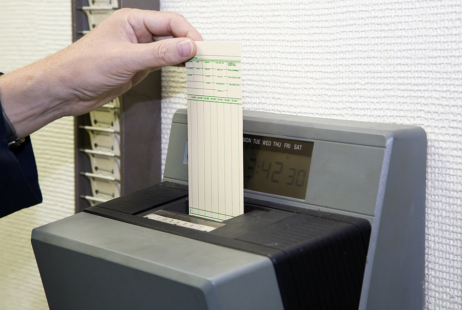 Worker's left hand slips time sheet into punch clock