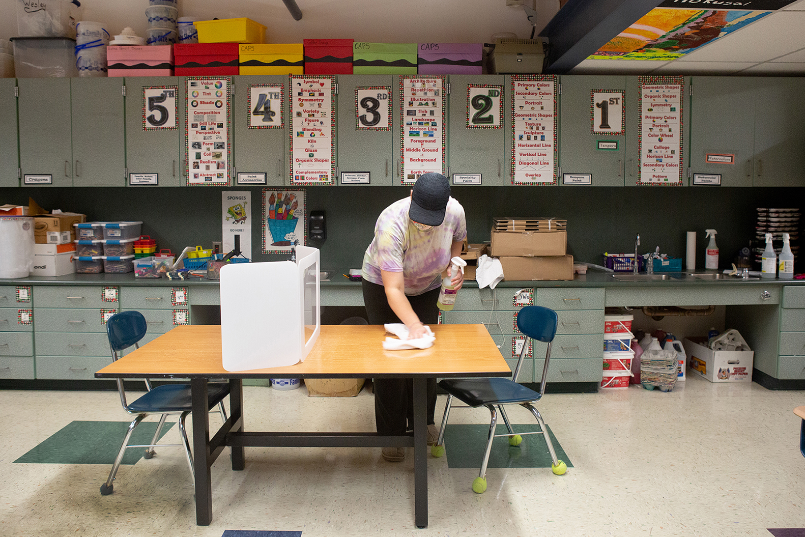 Elementary school custodian wipes table in classroom