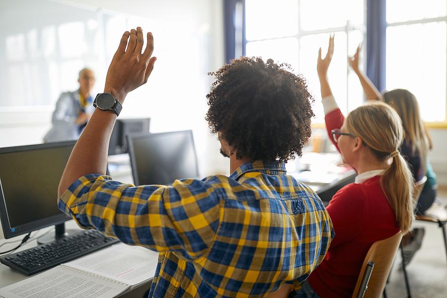 Students with hands raised in classroom