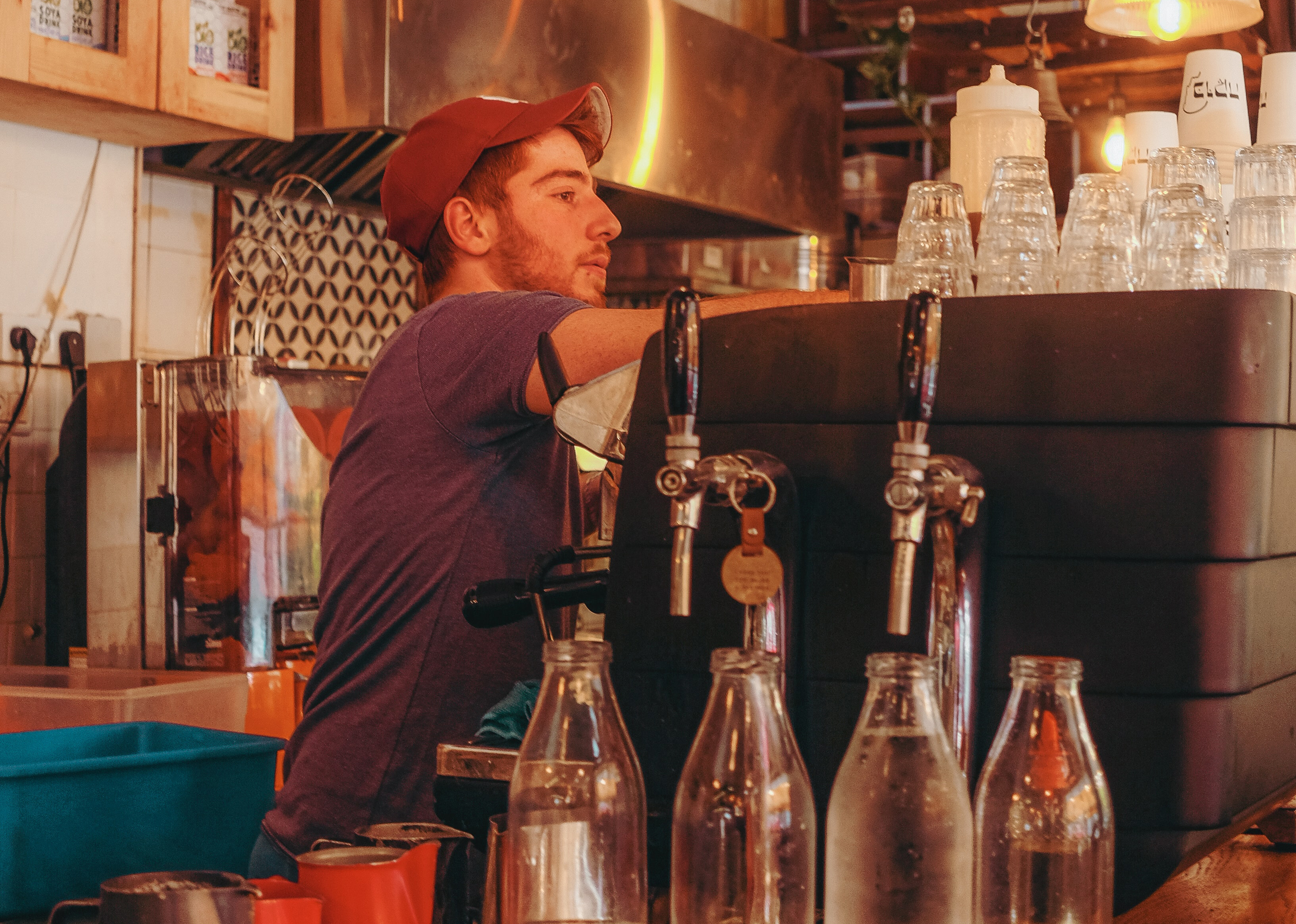 Young man barista working behind bar at coffee shop