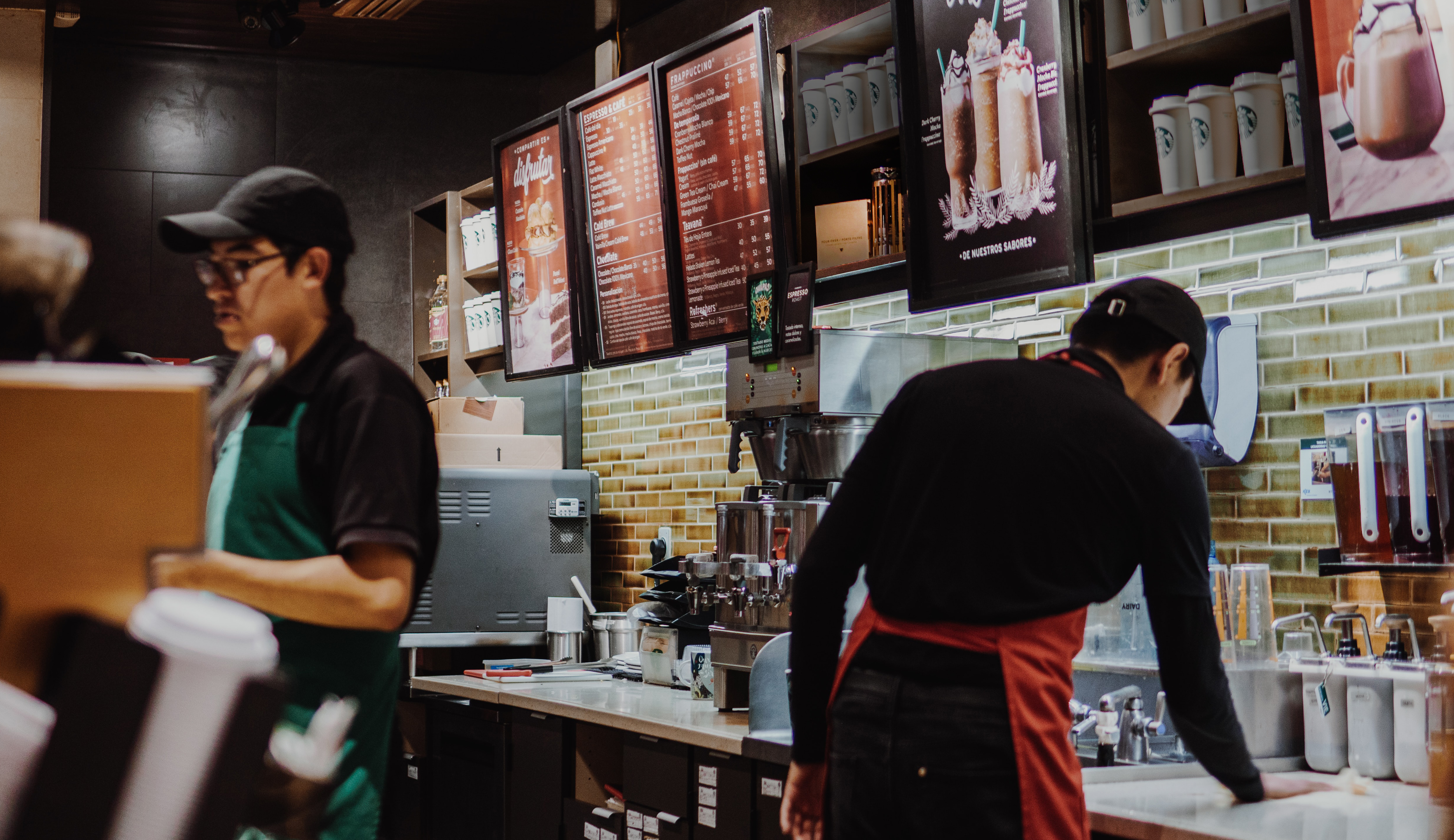 Two baristas work behind the counter of a coffee shop