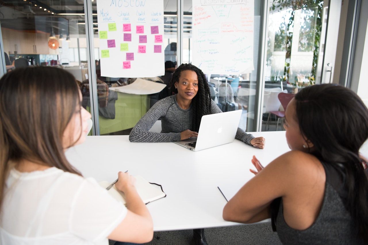 Women discuss work over conference room table