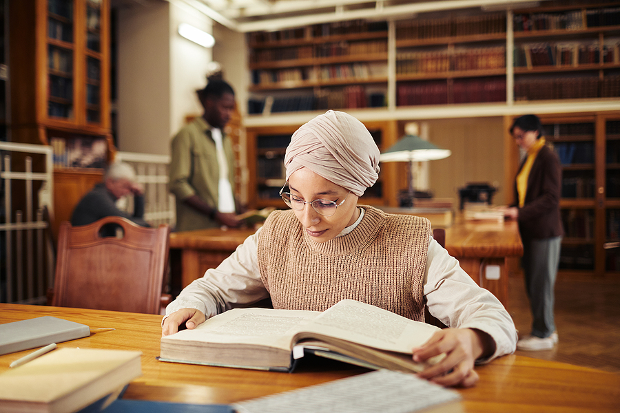 Woman in headscarf studies in library