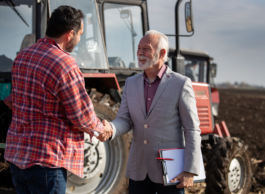 Farmer shakes hands after deal in front of tractor