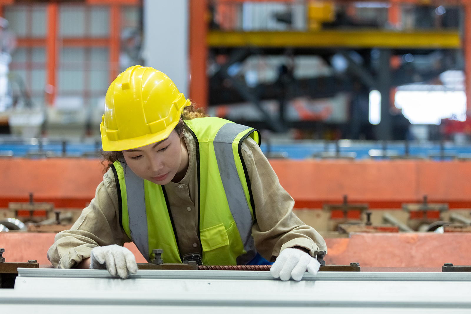 Factory worker examines metal in manufacturing process