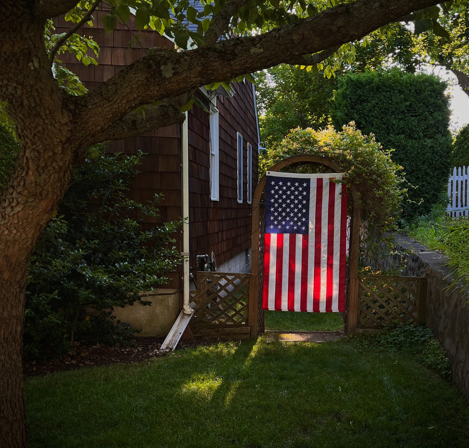 Backyard with U.S. flag hanging in archway while family celebrates Labor Day out of camera