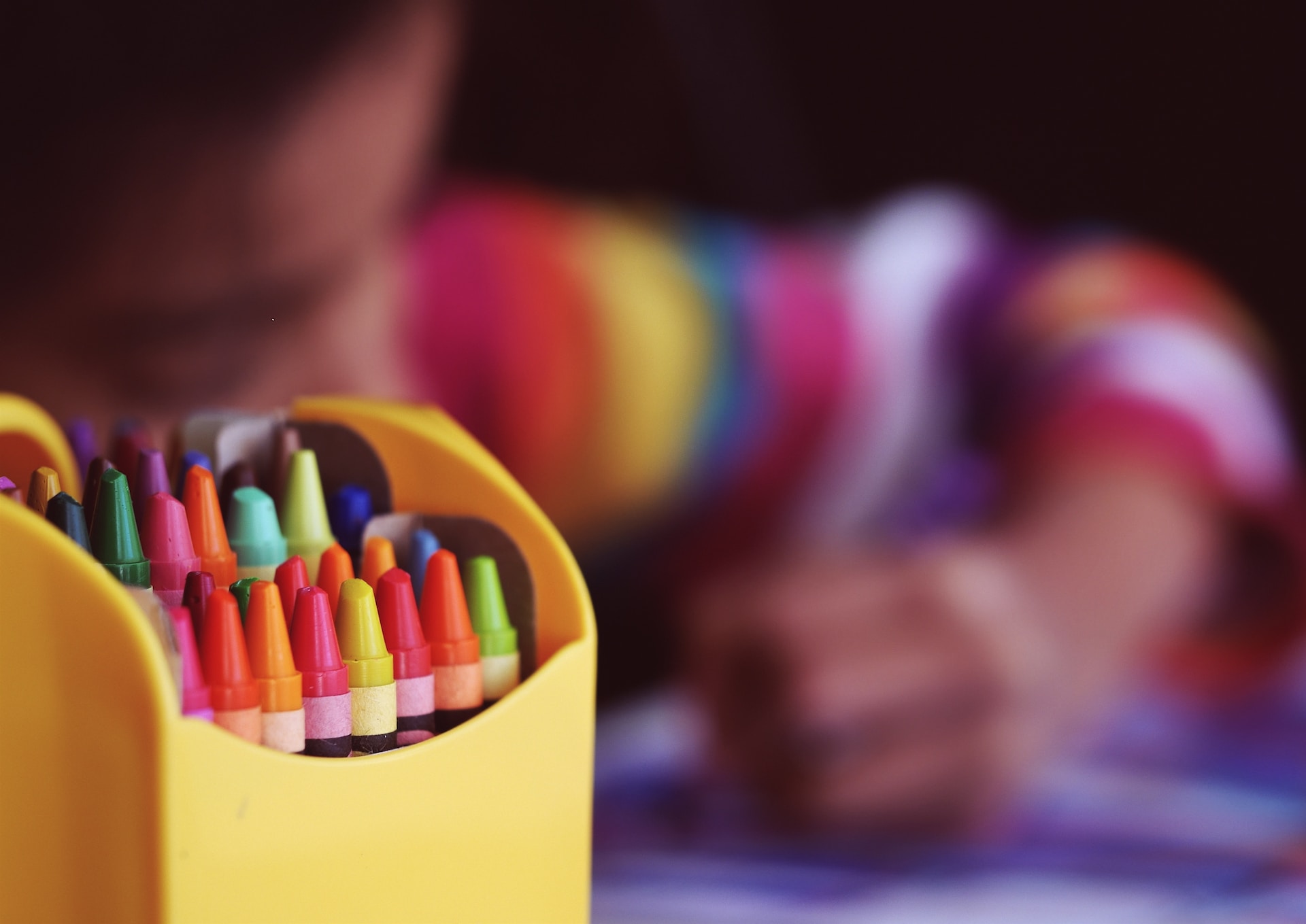Child at day-care center colors with crayons, crayons in foreground in focus