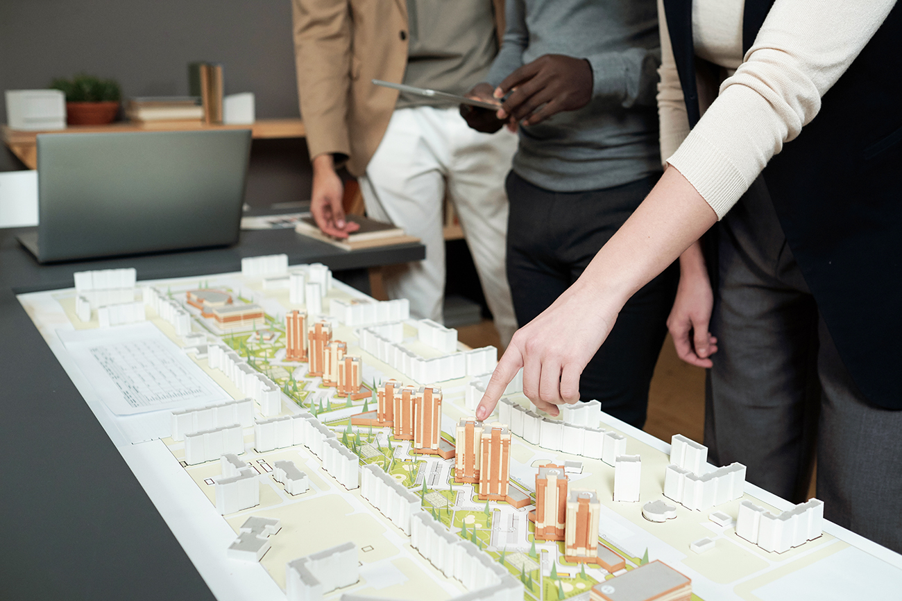 Woman points at building in a development model while others look on