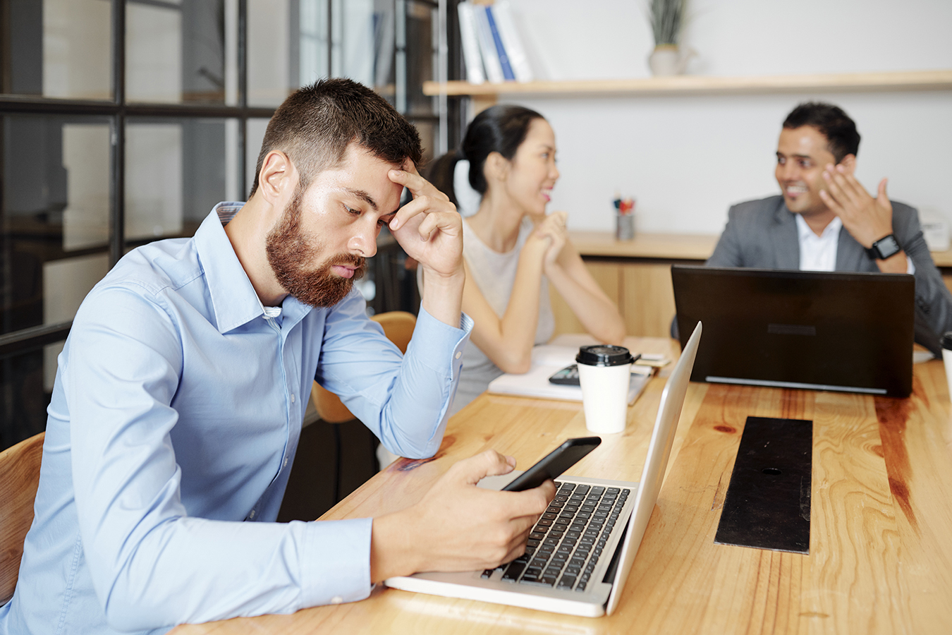 Man looks at phone during meeting