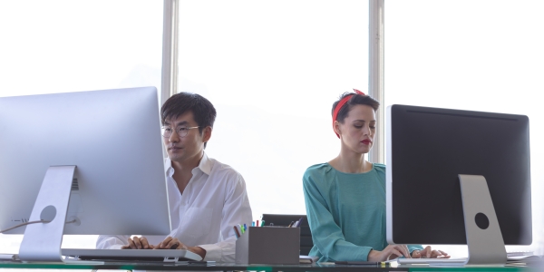 Two workers in front of desktop computers
