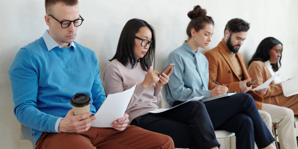 Several applicants sitting along wall while waiting for their turn for interviewby Pressmaster