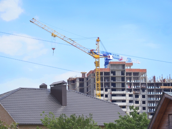 Apartment building under construction with house roof in foreground