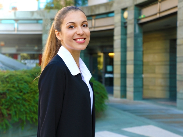 Smiling young woman in business dress in front of office