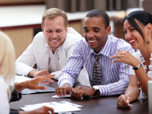A group of people at a business meeting. There are four people, all appear happy. 