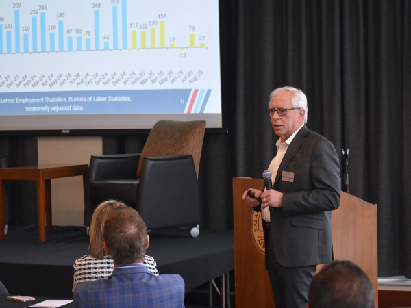 Upjohn Institute President Mike Horrigan standing in front of line graphs depicting economic information
