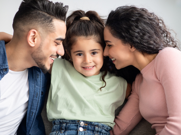  a man and woman, both with dark, wavy hair, embracing a young child with curly brown hair. By Prostock-studio and Envato