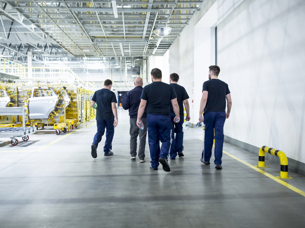 a group of workers walking together in a factory setting.