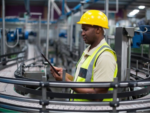 Manufacturing worker in hi-viz clothing and hardhat studies instructions