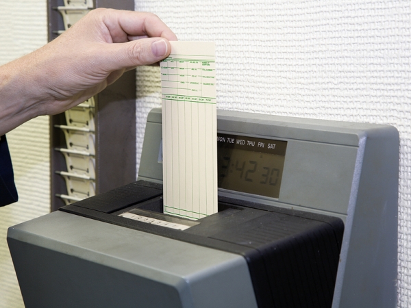 Worker's left hand slips time sheet into punch clock