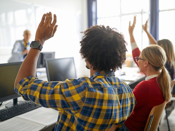 Students with hands raised in classroom