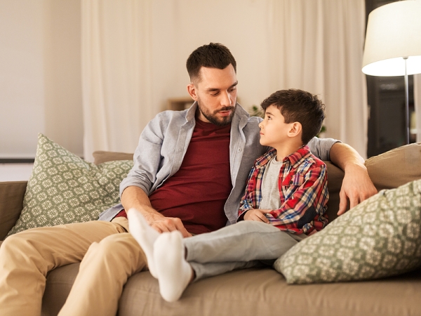 Father talks with son on couch