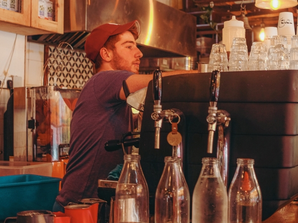 Young man barista working behind bar at coffee shop