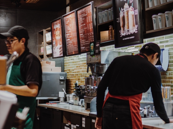Two baristas work behind the counter of a coffee shop