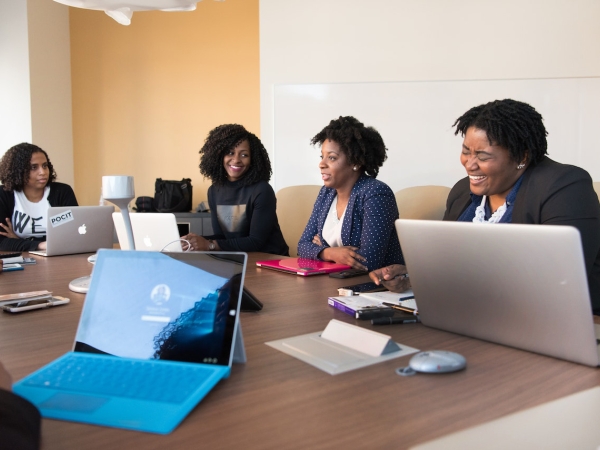 Women laugh in a meeting, board room with laptops
