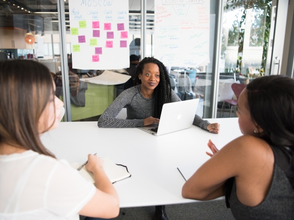 Women discuss work over conference room table
