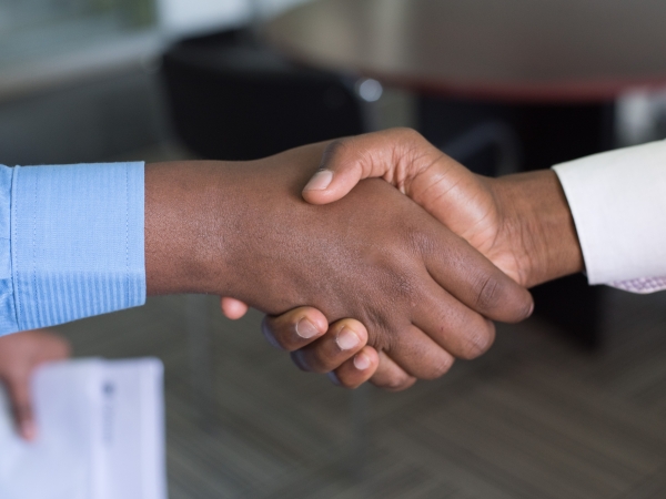 Closeup of handshake among formally dressed African-American men in office setting