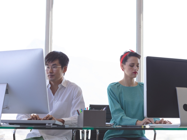 Two workers in front of desktop computers