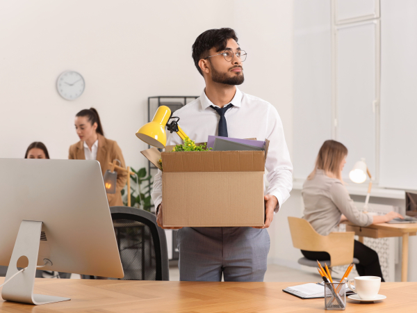 Young Man Leaving Job Carrying Box in Officeby africaimages