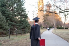 College graduate in cap and gown looking back at his university