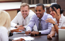 A group of people at a business meeting. There are four people, all appear happy. 