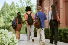 Rear View of Diverse College Students Walking to Class on Campusby AnnaStills