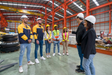 a group of workers speaking together in a factory setting. 